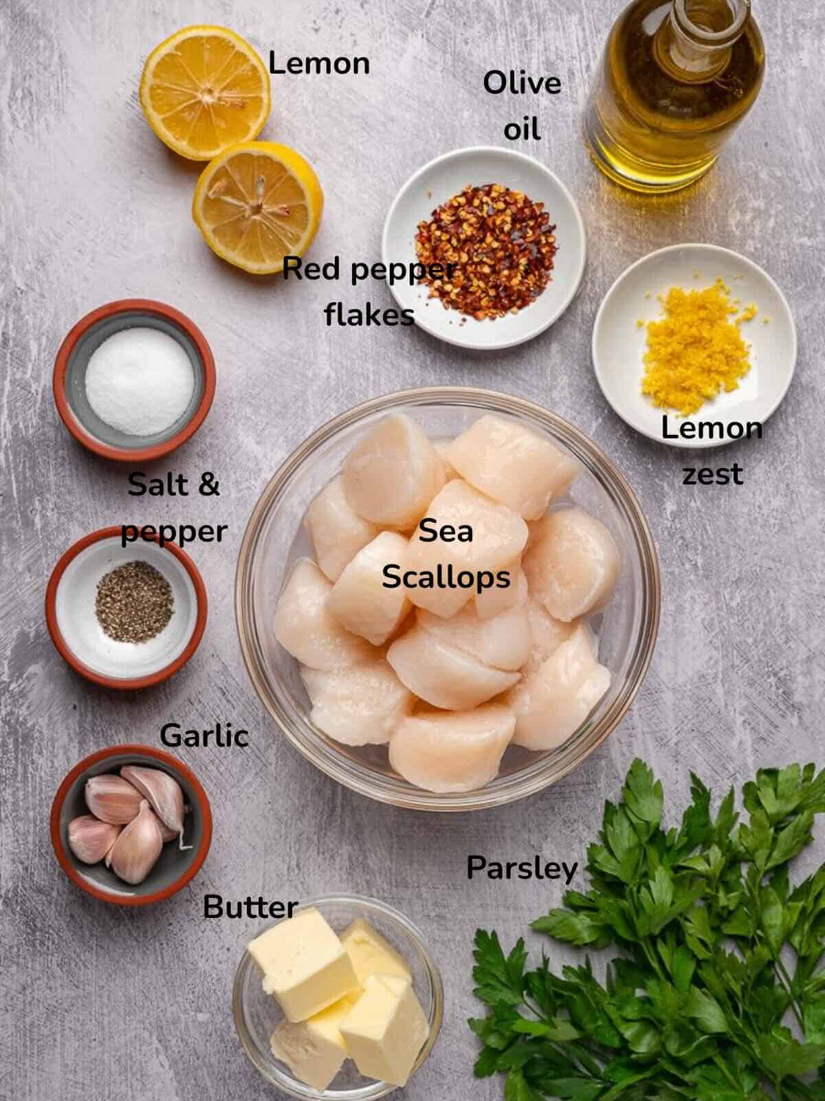 Ingredients to make garlic butter seared scallops include fresh sea scallops, butter, garlic, parsley, lemon juice, and lemon zest.