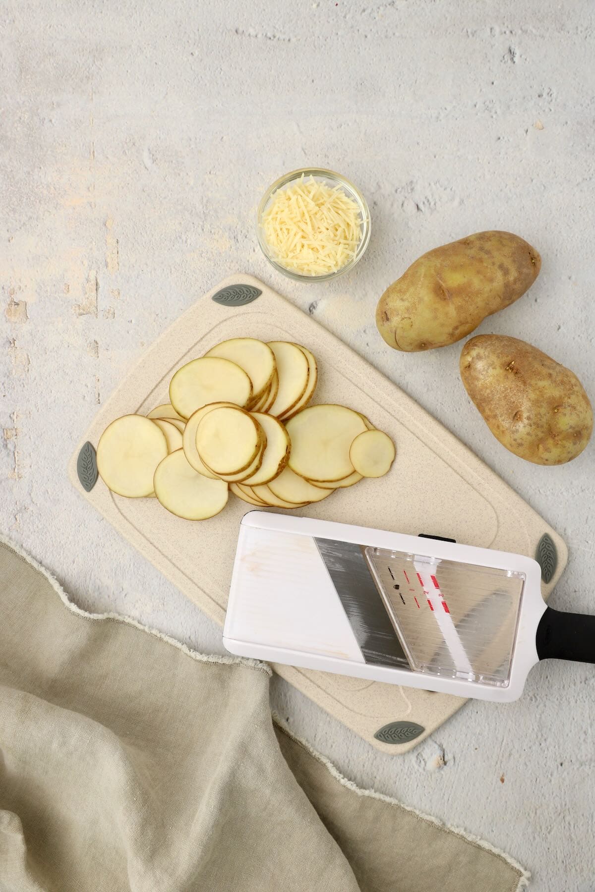 Using a mandolin to slice potatoes on a cutting board.