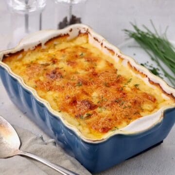Baked cheesy scalloped potatoes in a blue ceramic baking dish.