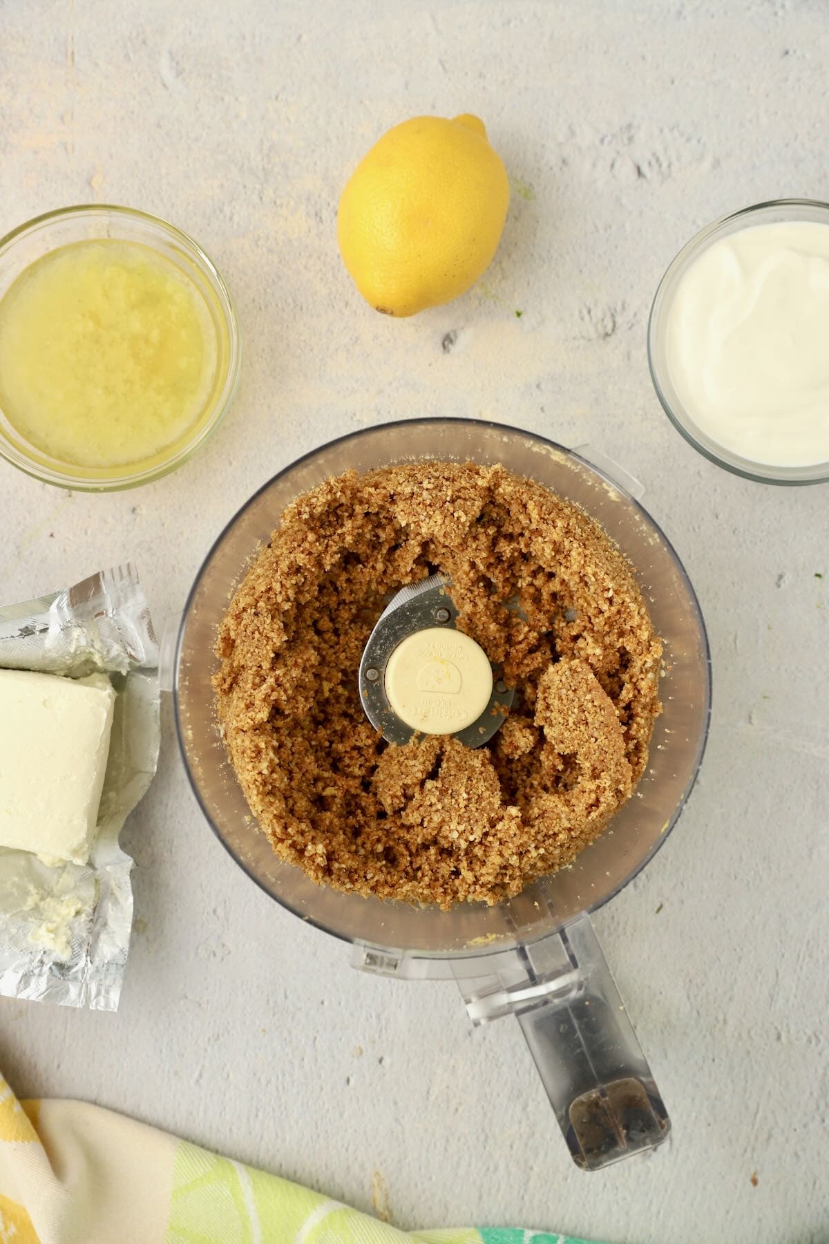A food processor full of processed graham cracker crumbs, nuts, and butter.