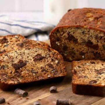 A loaf of chocolate chunk banana bread sliced on a cutting board.