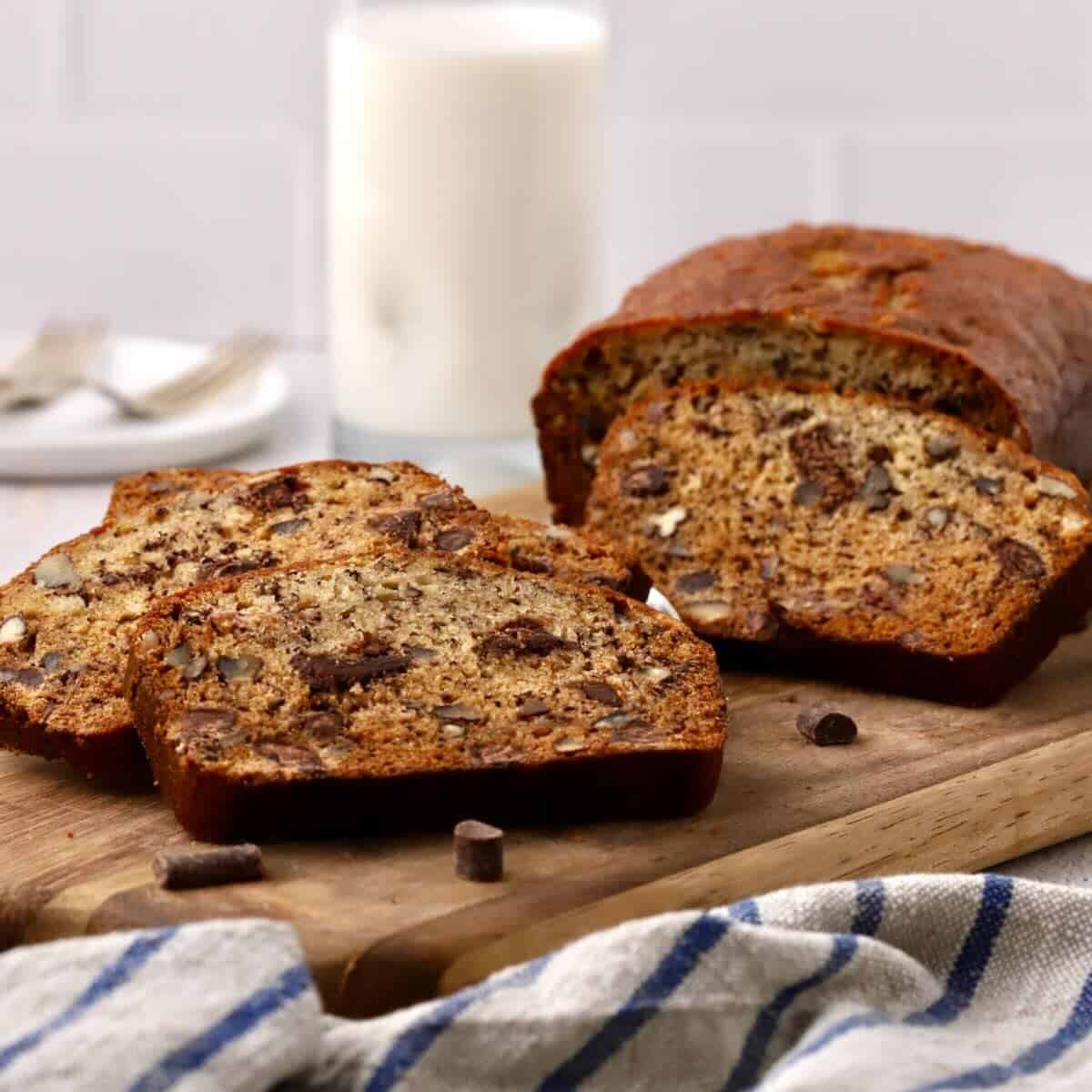 A loaf of chocolate chunk banana bread with slices cut on a cutting board.