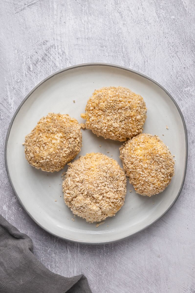 Four burrata balls coated in panko are ready to freeze.