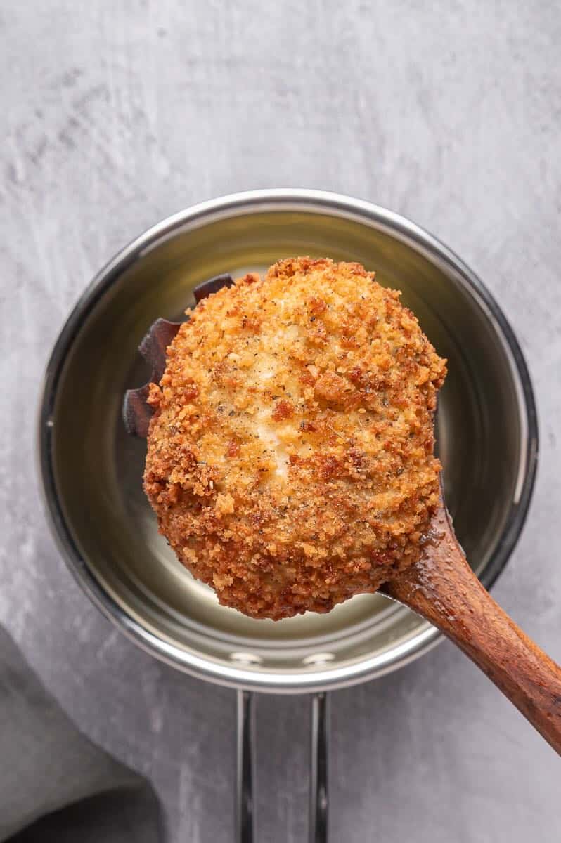 A fried burrata ball just removed from the oil.