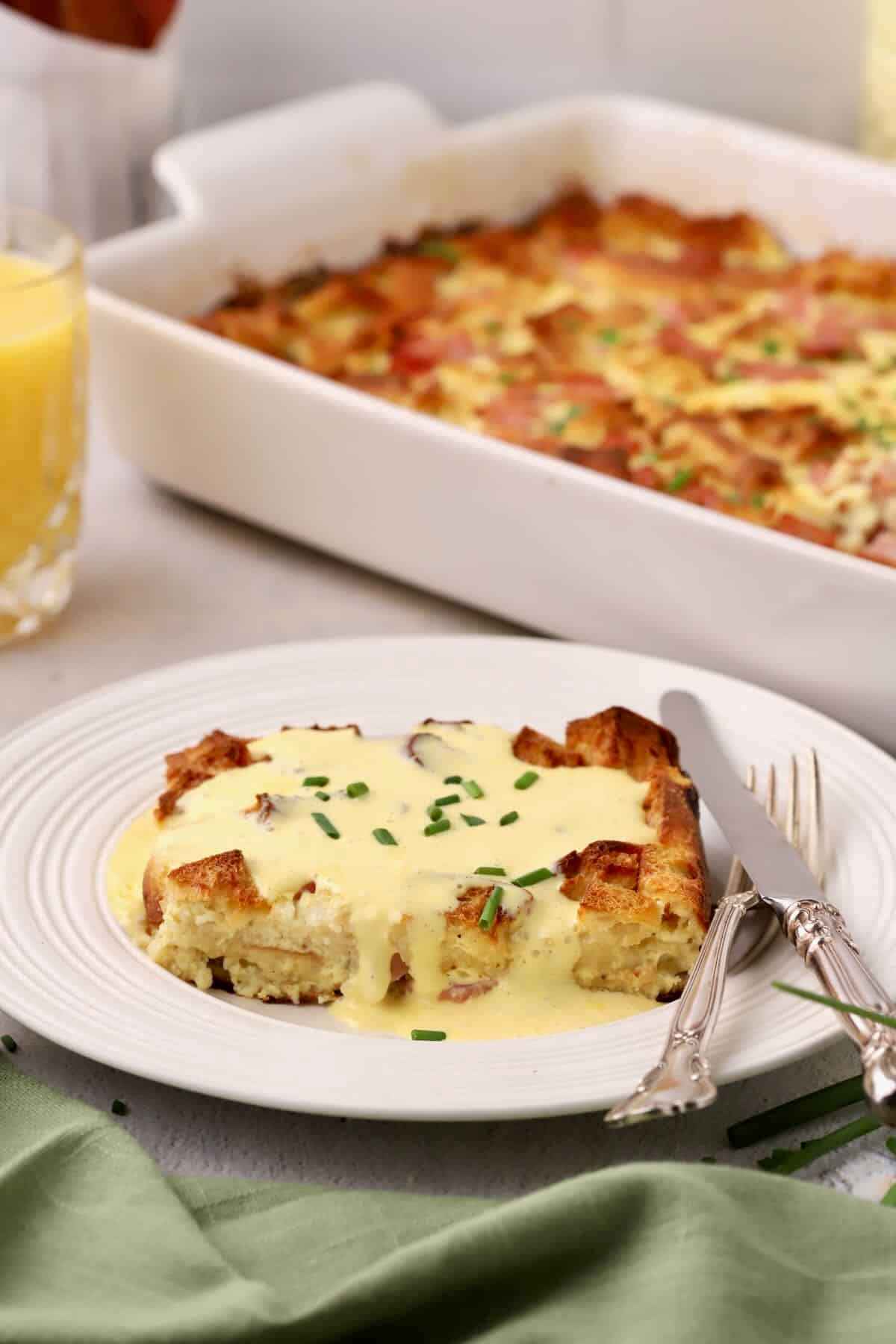 A serving of eggs benedict casserole on a plate topped with hollandaise sauce.