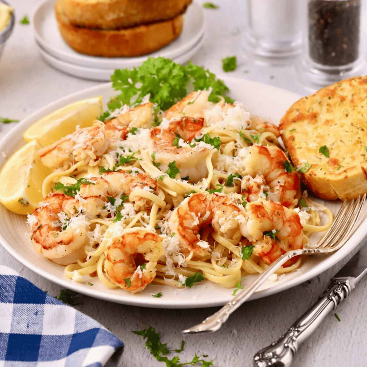 A plate full of garlic butter noodles with shrimp with a piece of garlic toast on the side.