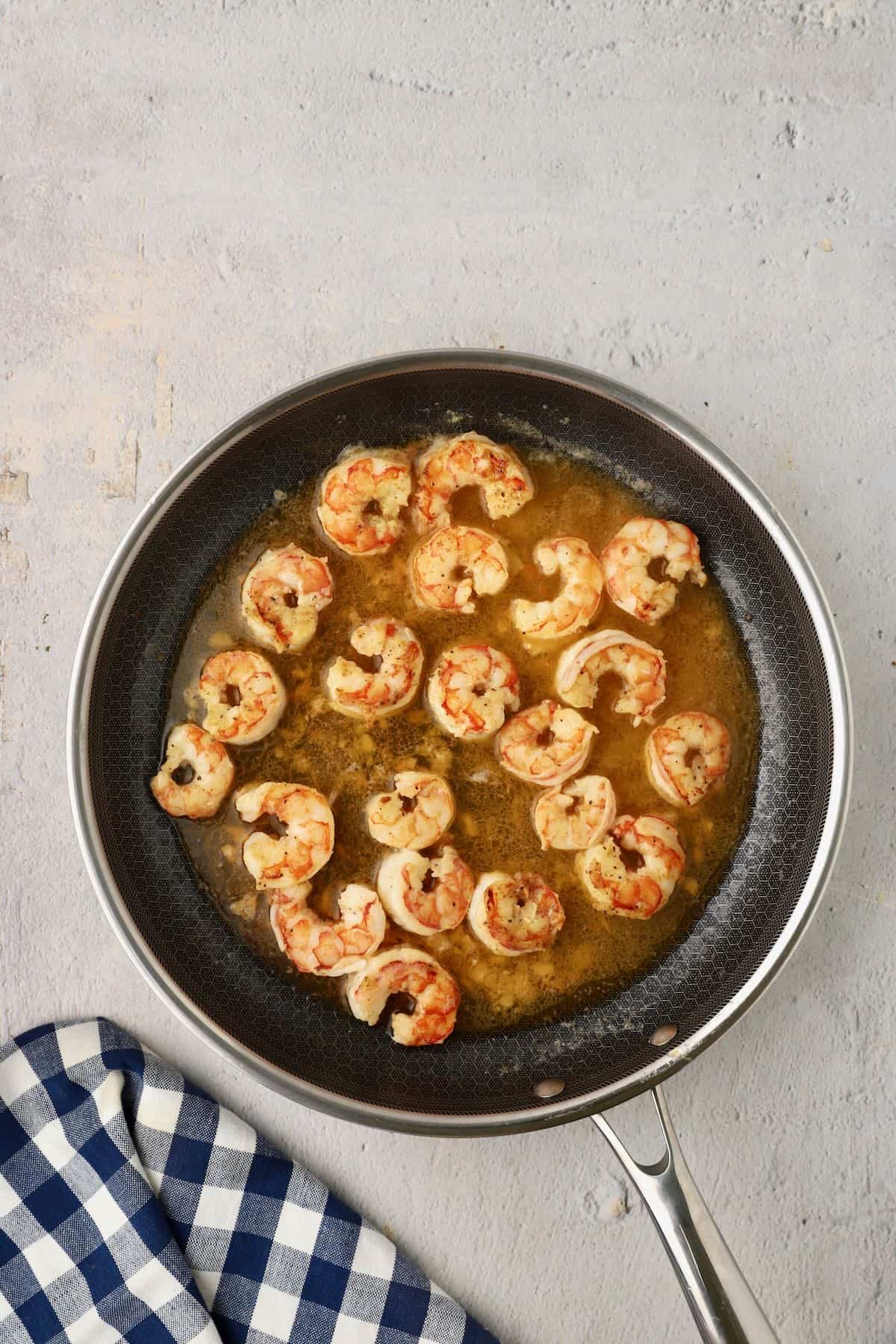 Royal red shrimp cooking in a butter, wine and lemon juice sauce in a skillet.