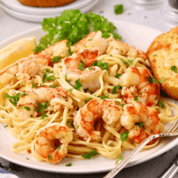 Garlic Butter Noodles with Shrimp on a white plate, garnished with parsley.