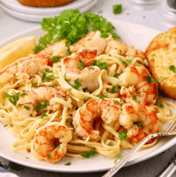 Garlic Butter Noodles with Shrimp on a white plate, garnished with parsley.