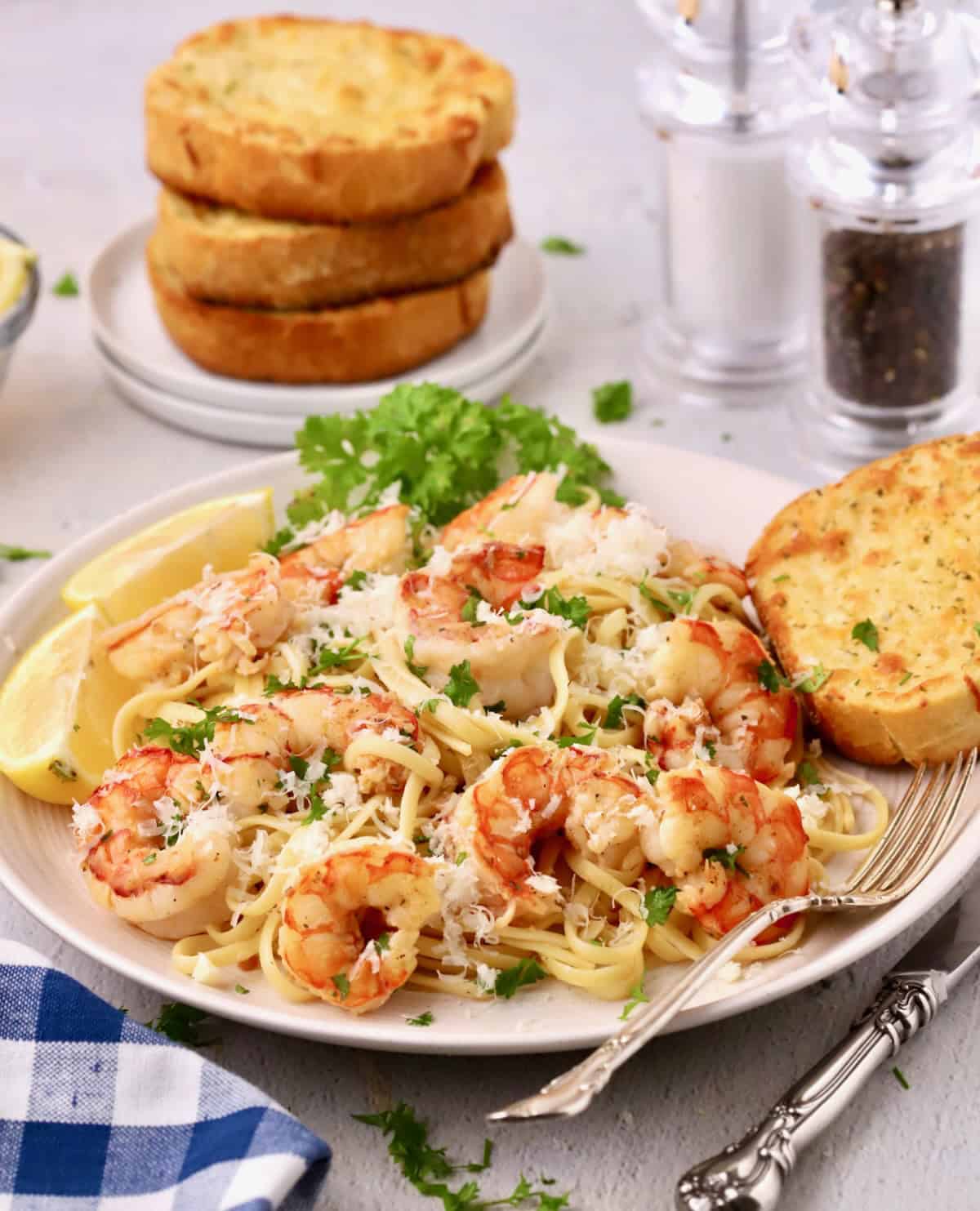 Garlic Butter Noodles with shrimp on a plate topped with parsley and grated patmesan cheese.