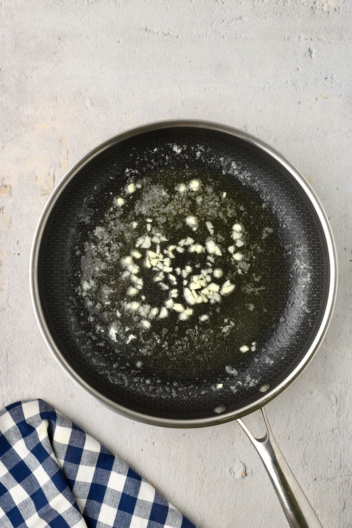 Minced garlic cooking in butter in a skillet.