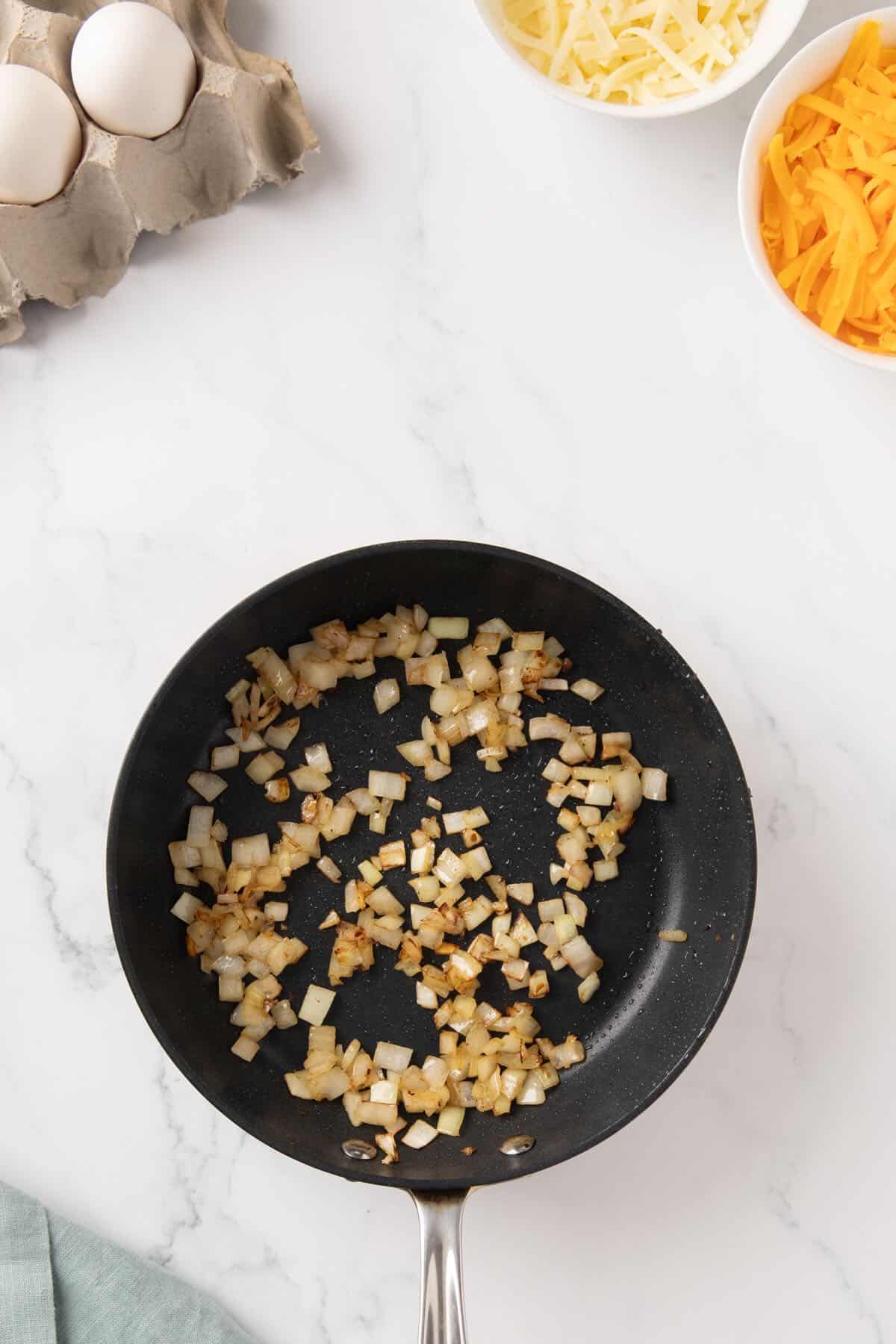Chopped onions are cooking in a skillet.