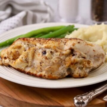 Stuffed Chicken Breast with cornbread stuffing on a plate with green beans and mashed potatoes.