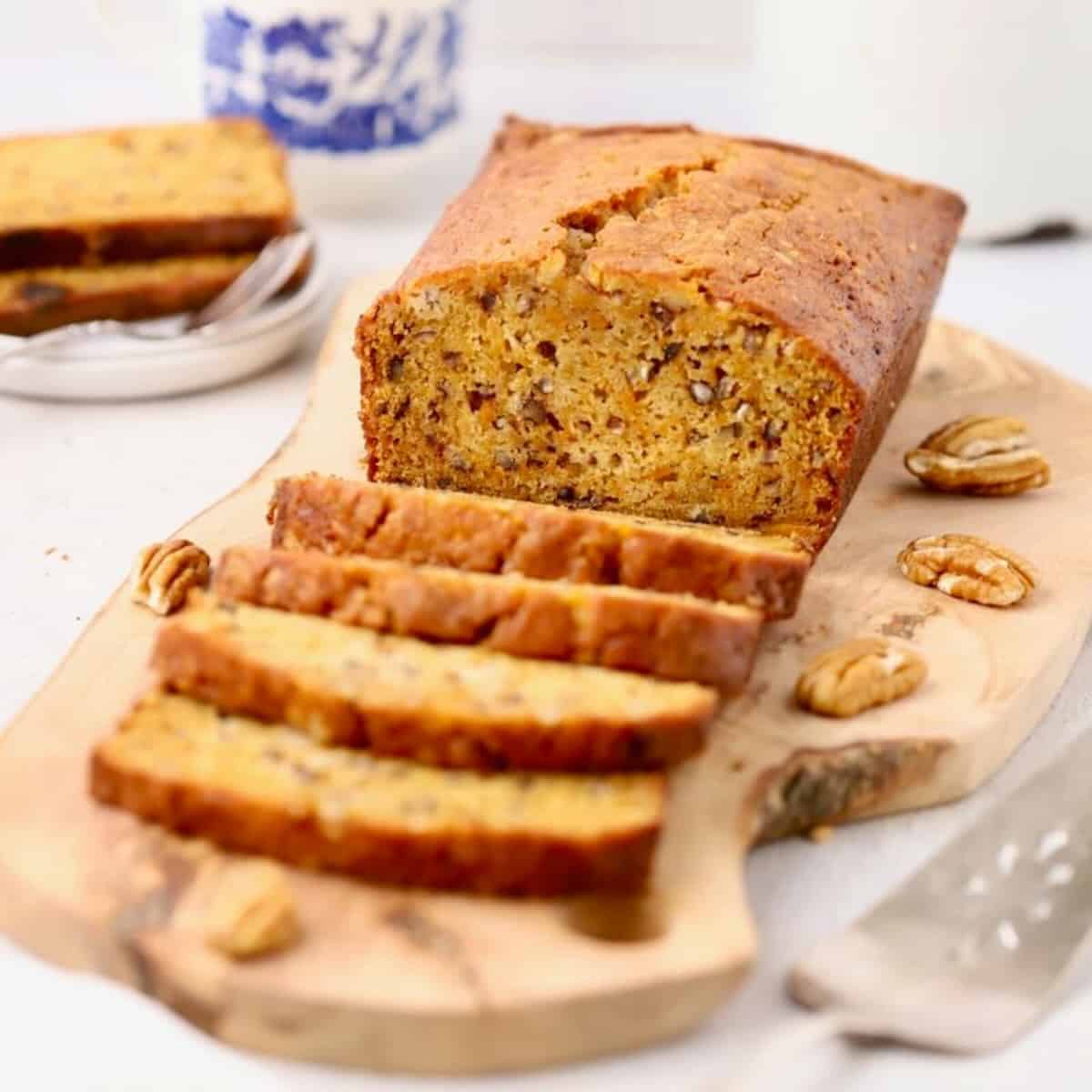 A loaf of sweet potato bread on a cutting board with several slices already cut.