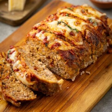 A 1-pound meatloaf sliced on a cutting board, topped with melted cheese and glaze.