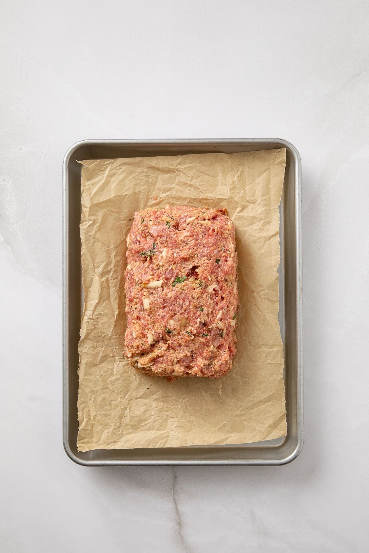 Meatloaf is shapped into a 6x4-inch loaf on a sheet pan.