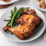 Air fried chicken leg quarter on a plate with green beans and potatoes.