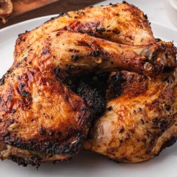 Three air-fried chicken leg quarters on a white plate.
