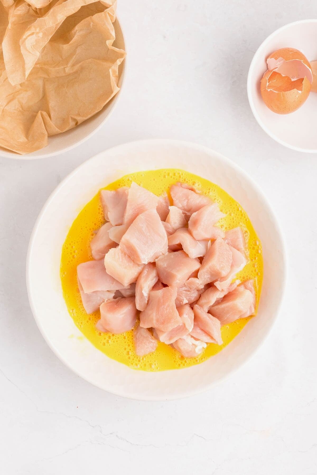 Cut up pieces of chicken in a bowl with eggs.