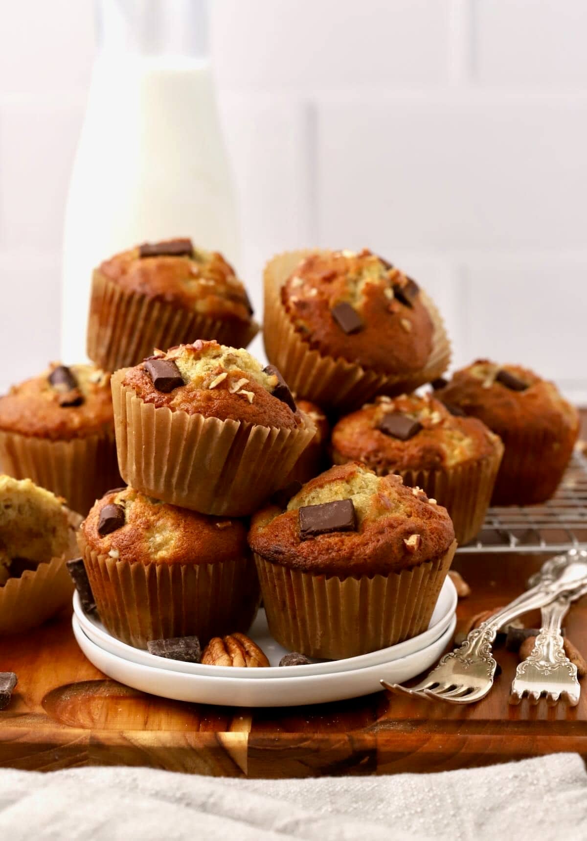 A plate full of chocolate chunk banana muffins stacked on top of each other.