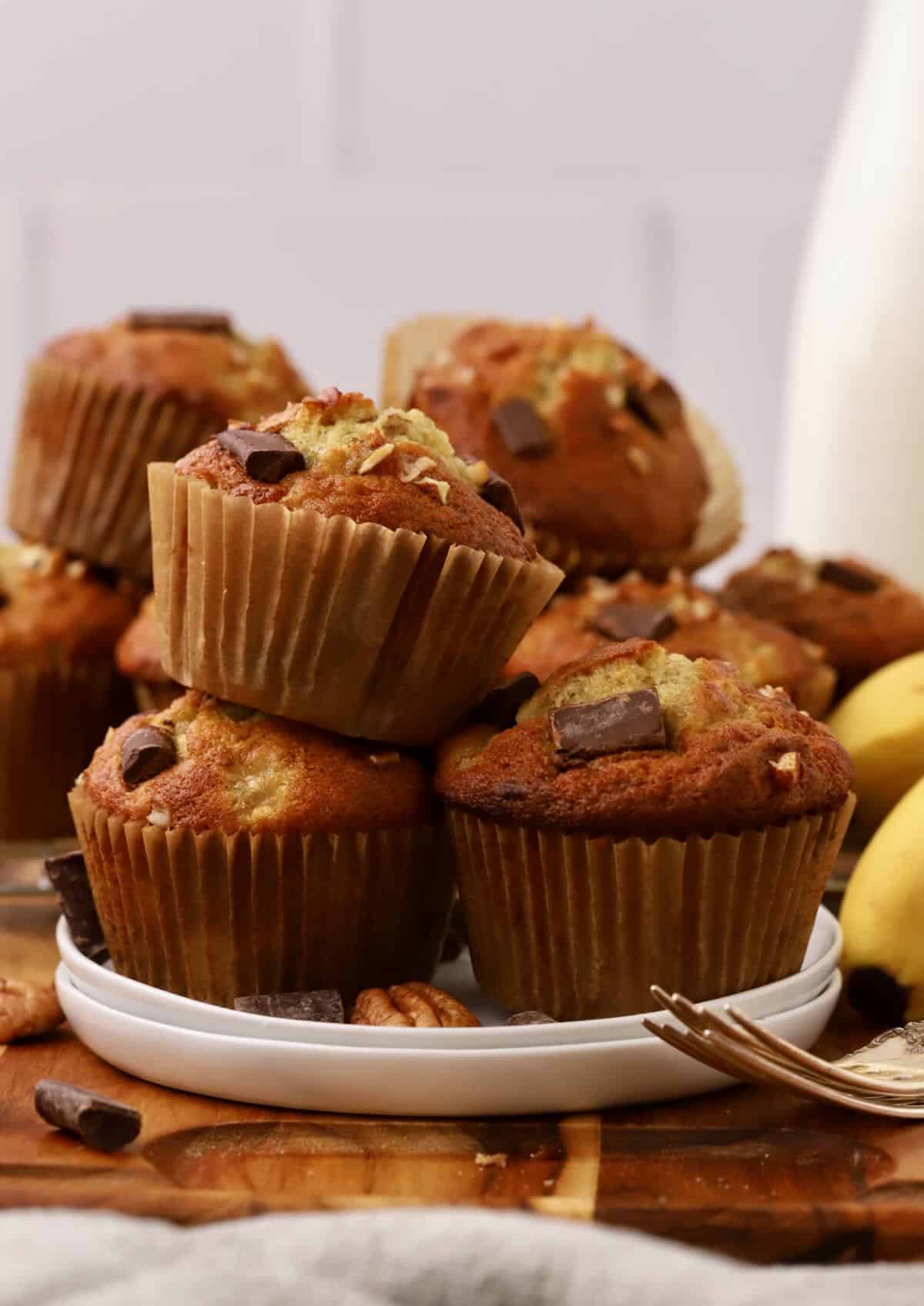 A plate full of chocolate chunk banana muffins with pecans.  