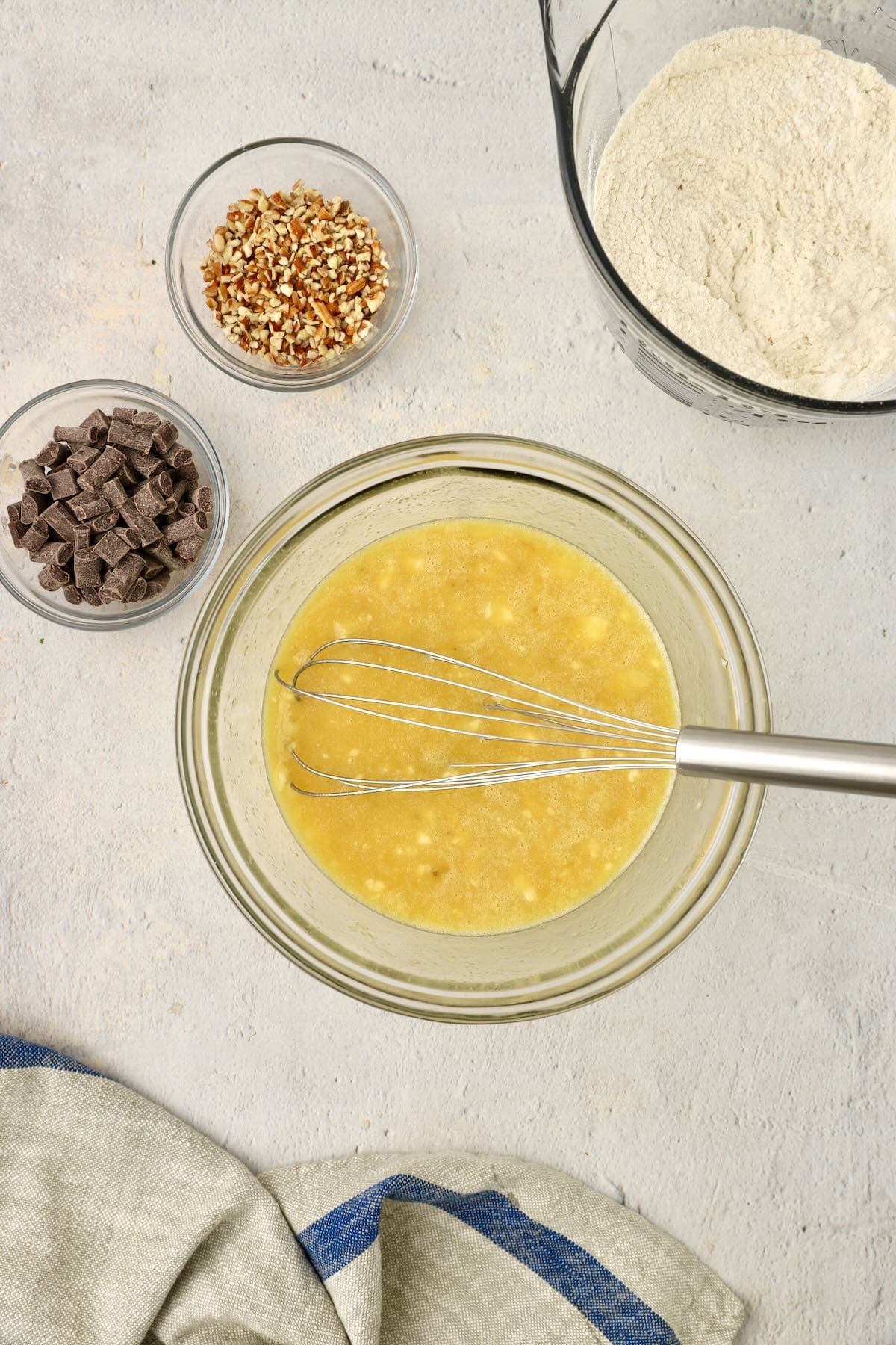 Mixing eggs, bananas, oil, and butter in a bowl.