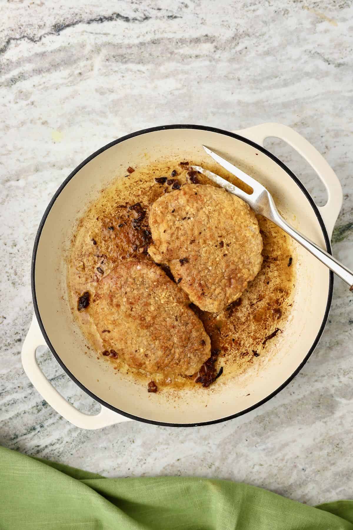 Tenderized steaks are browning in a skillet.