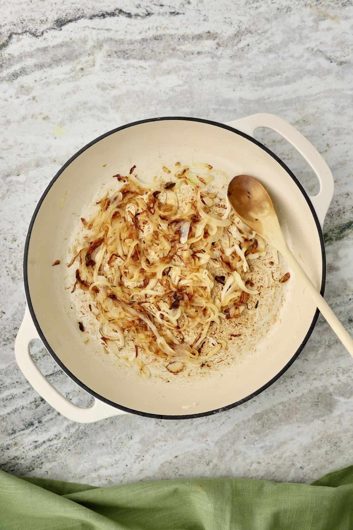 Sliced onions are cooking in a skillet.