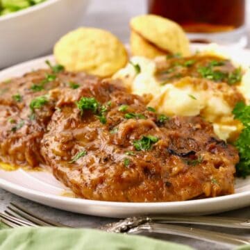 Country-style steak smothered with onion gravy on a white plate with mashed potatoes.