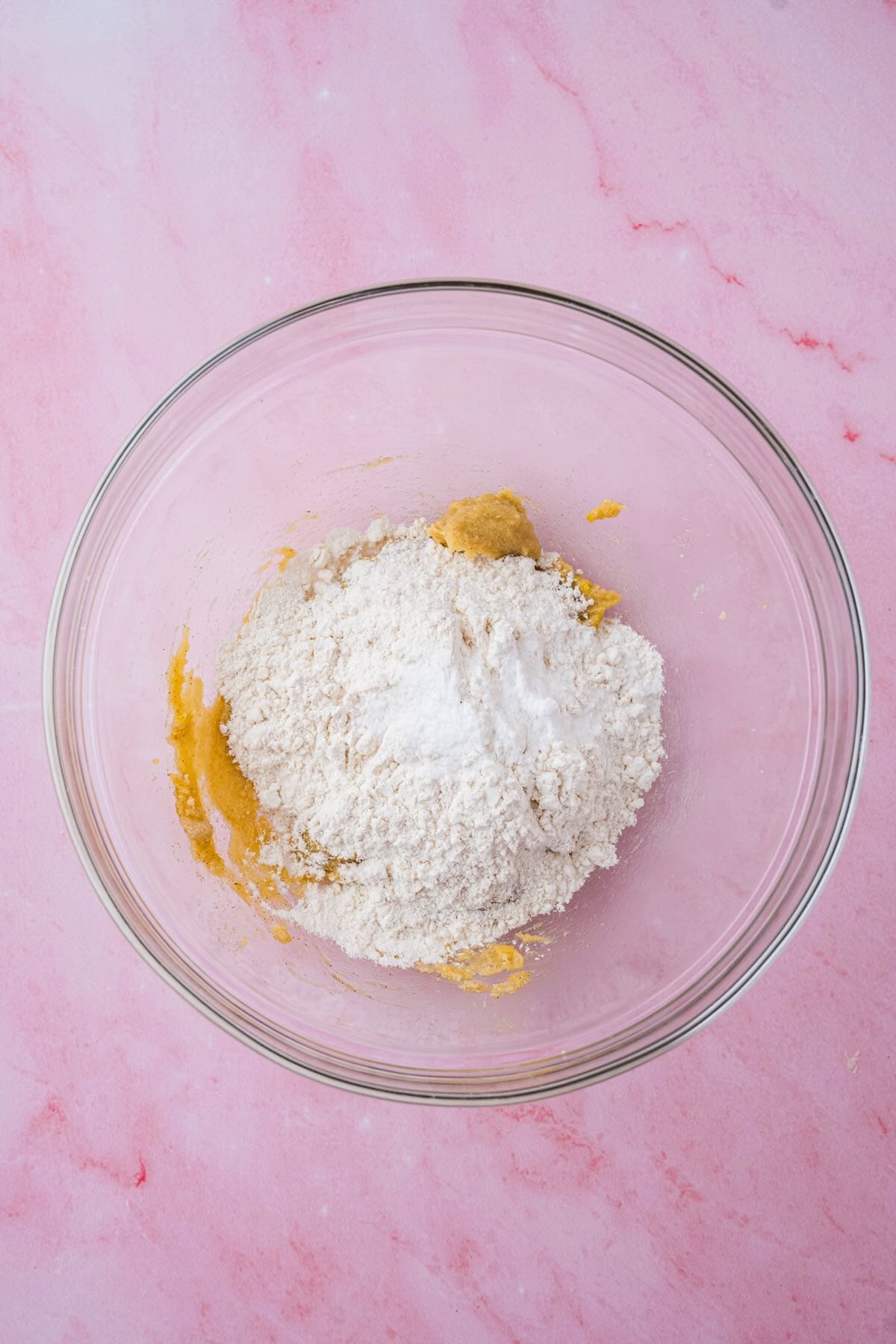Flour and leavening agents added to a bowl with creamed butter and sugar.
