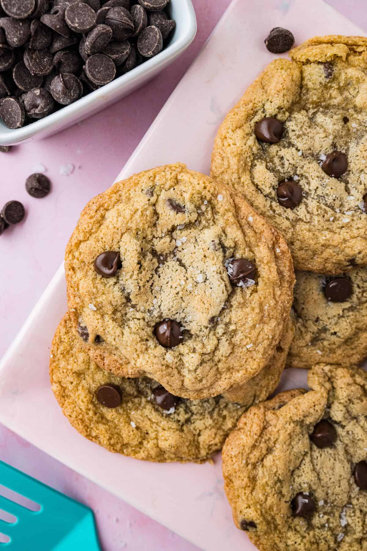 Small batch chocolate chip cookies next to a bowl of chocolate chips.