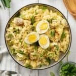 Deviled Egg Potato Salad garnished with paprika and sliced scallions.