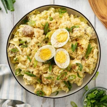 Deviled Egg Potato Salad garnished with paprika and sliced scallions.