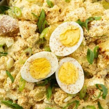 Deviled Egg Potato Salad garnished with paprika and sliced scallions.