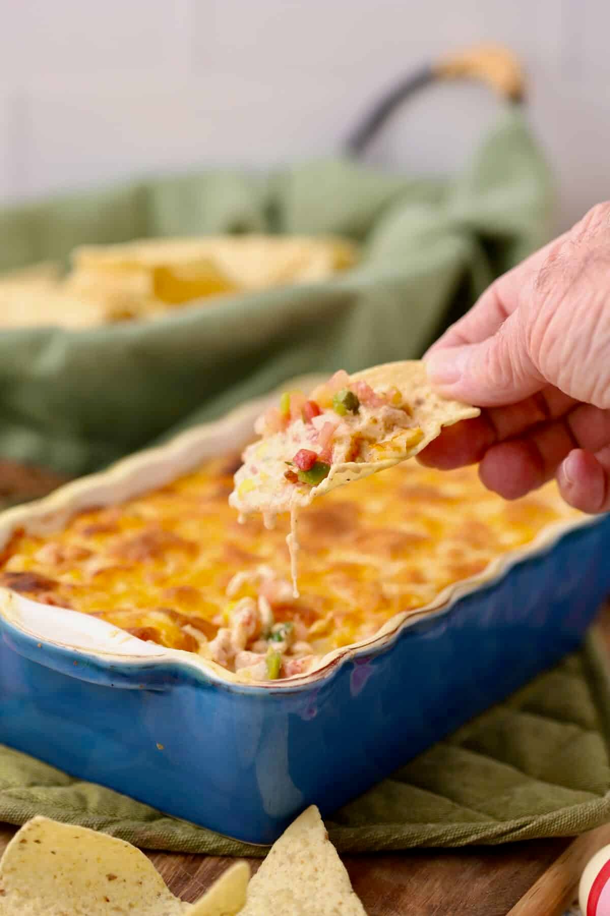 Hot corn dip in a blue baking dish with a scoop of dip.