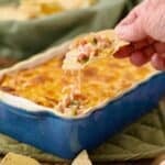 How corn dip in a blue baking dish with a scoop.