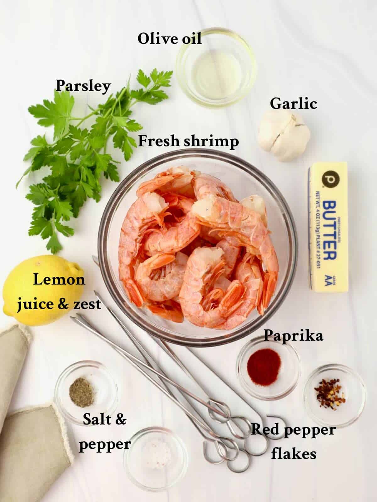Ingredients to make oven roasted shrimp skewers include fresh shrimp, garlic, lemon zest and juice, butter and olive oil.