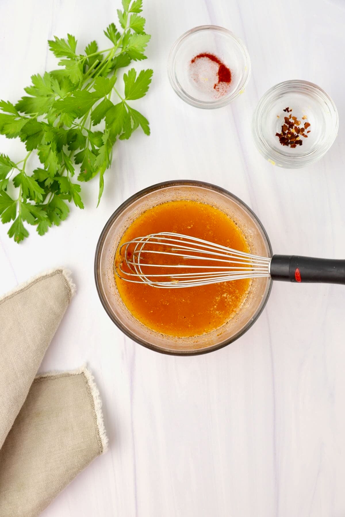 Garlic butter sauce in a small glass bowl with a whisk.