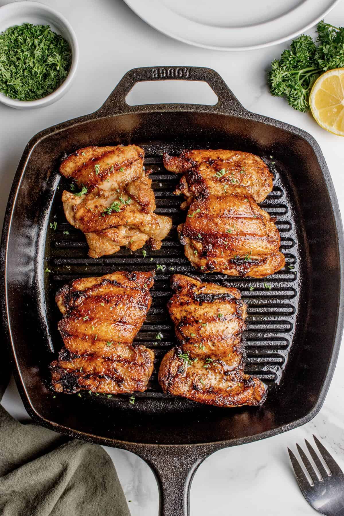 Juicy grilled boneless chicken thighs cooked on a cast-iron grill pan with dark grill marks