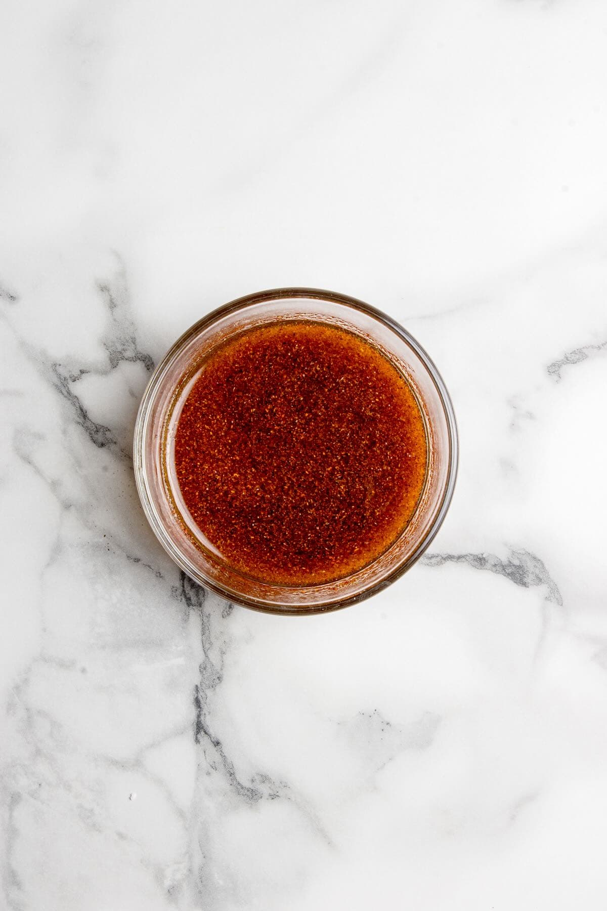 Marinade ingredients in a bowl include oil, garlic and onion powder and smoked paprika.