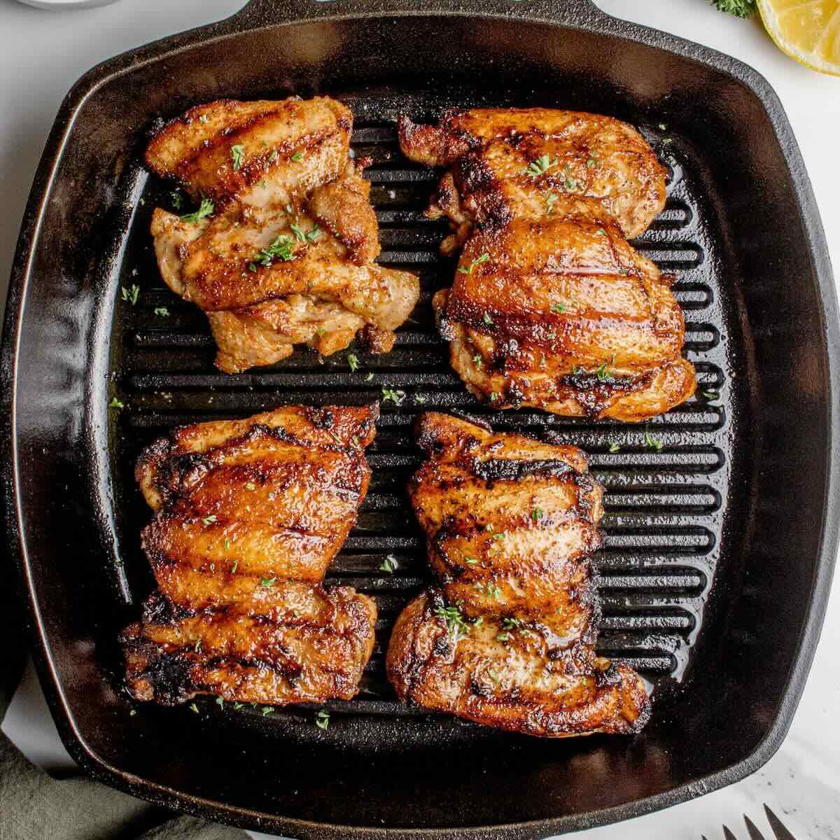 Juicy grilled boneless chicken thighs cooked on a cast-iron grill pan with dark grill marks