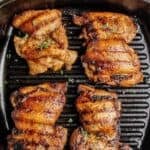 Four juicy grilled boneless chicken thighs cooked on a cast-iron grill pan with dark grill marks