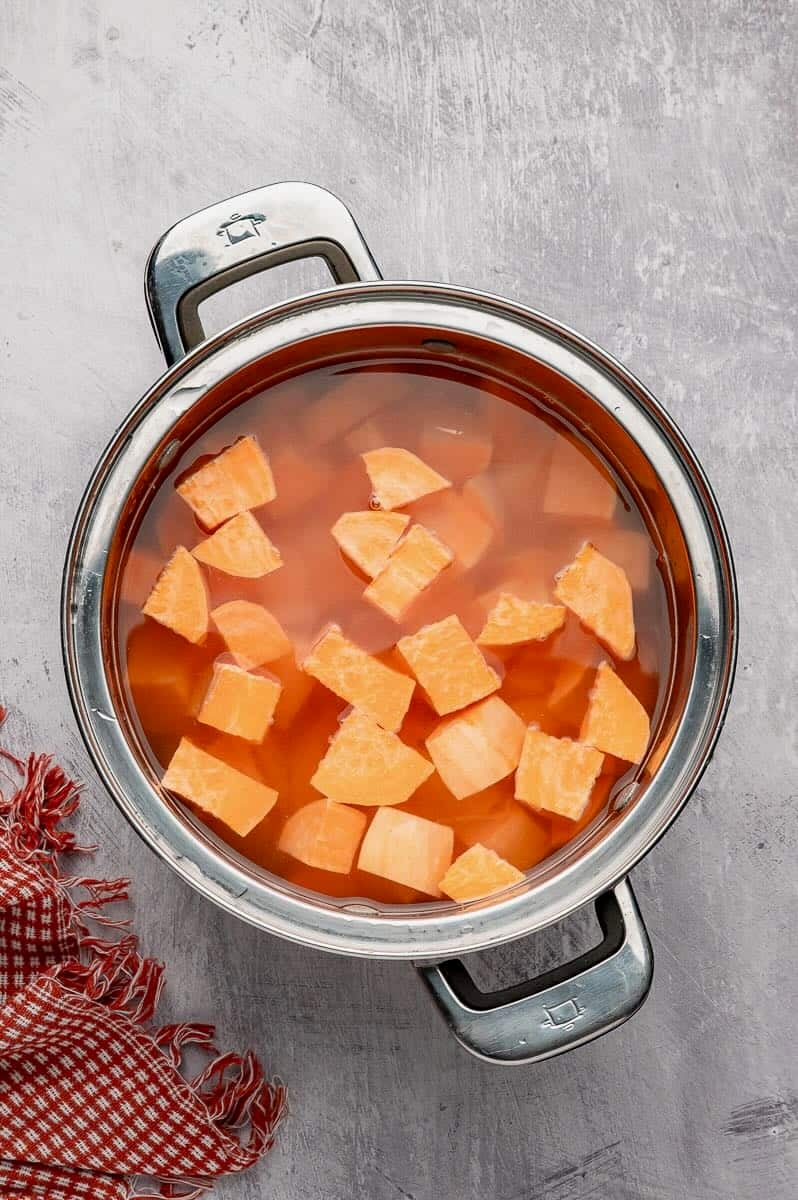 Cubed sweet potatoes are cooking in a saucepan.