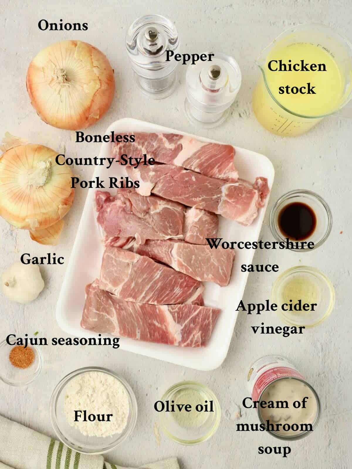 Ingredients for slow cooker country style ribs includes ribs, seasonings, onions, cream of mushroom soup and chicken stock.