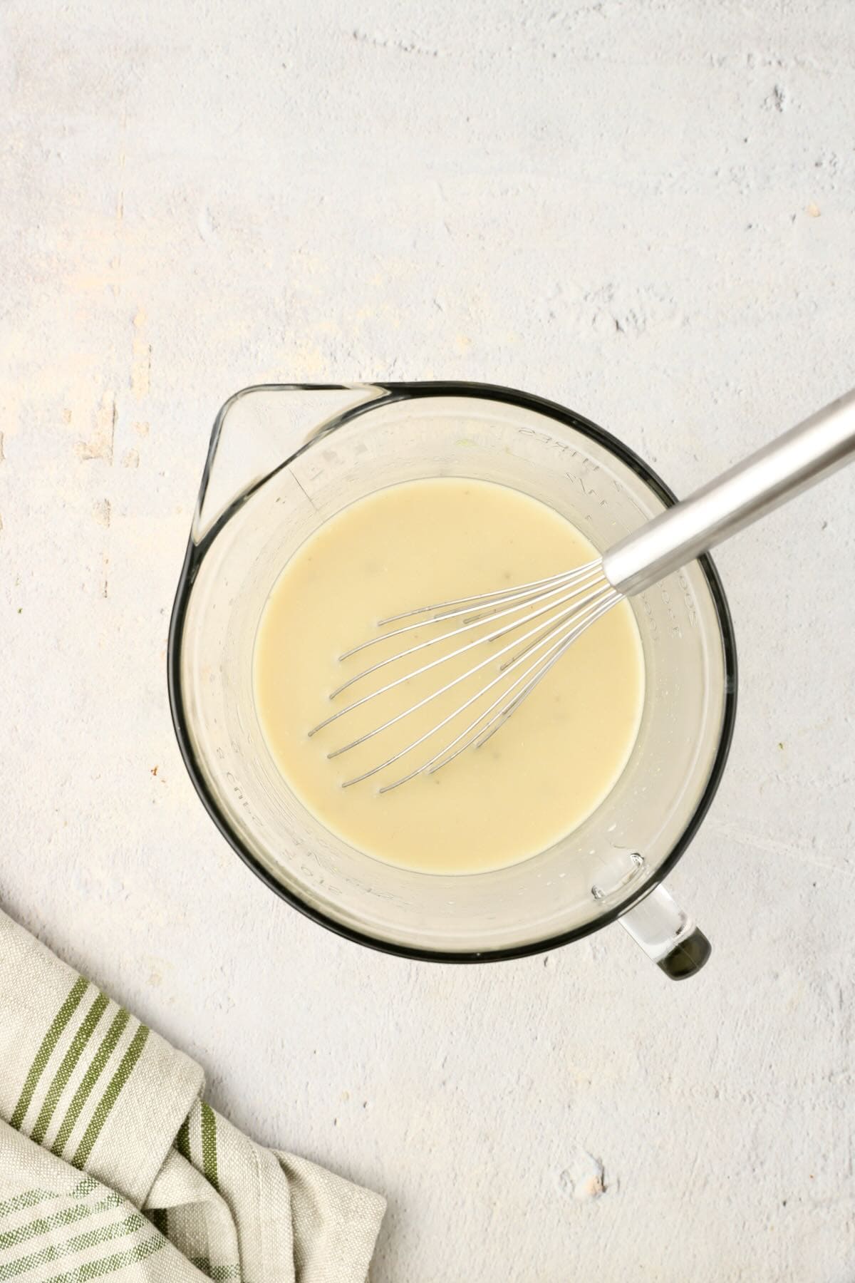 Chicken stock, cream of mushroom soup and seasonings in a glass bowl.