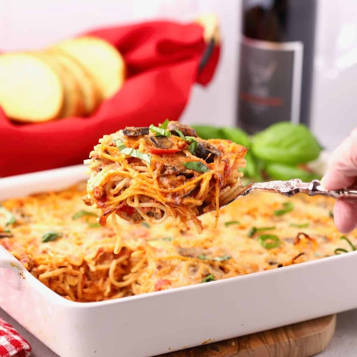 A large dish of spaghetti pie casserole with a large serving being taken out.