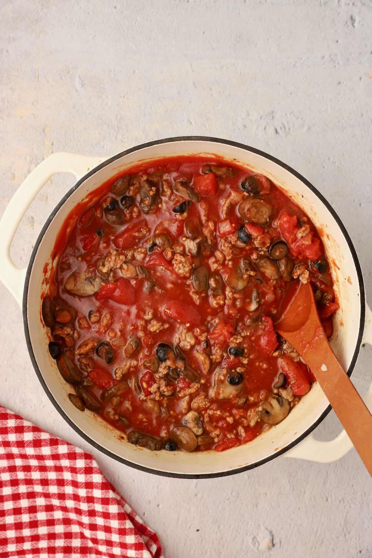 Two types of canned tomatoes and seasonings are added to the sausage mixture.