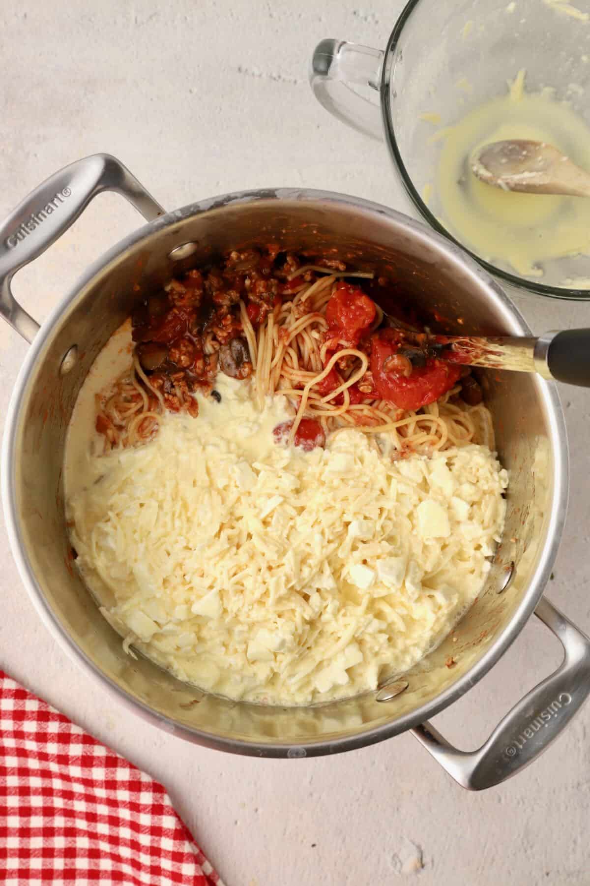 Spaghetti, meat sauce, and eggs, cream, and cheeses in a large Dutch oven.