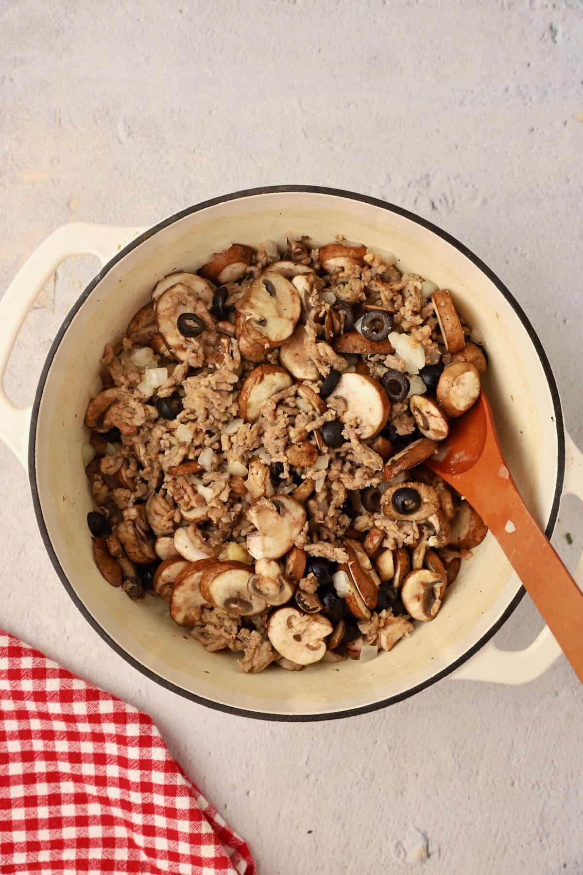 Mushrooms and olives are added to the sausage.