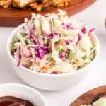 A white bowl full of spicy coleslaw with cabbage, onions, and jalapeno peppers.